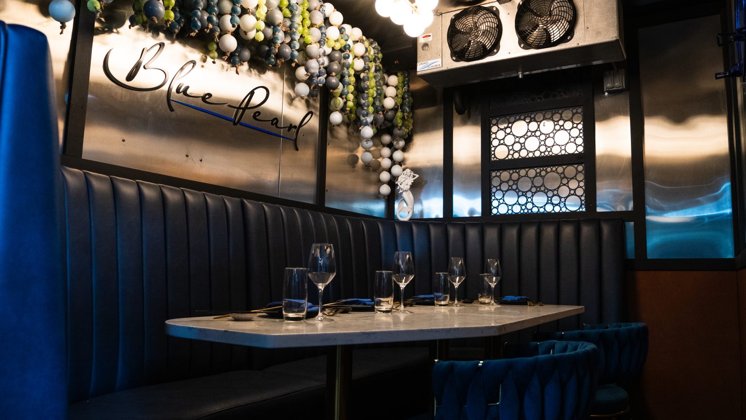 The Icebox set for six, its marble table and navy banquette beneath the original freezer fans